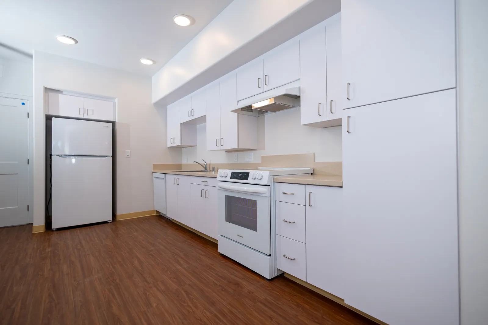 Kitchen cabinetry with white slab doors and light countertops installed in all 50 units at Pismo Terrace apartment complex in Pismo Beach CA by California Woodworking
