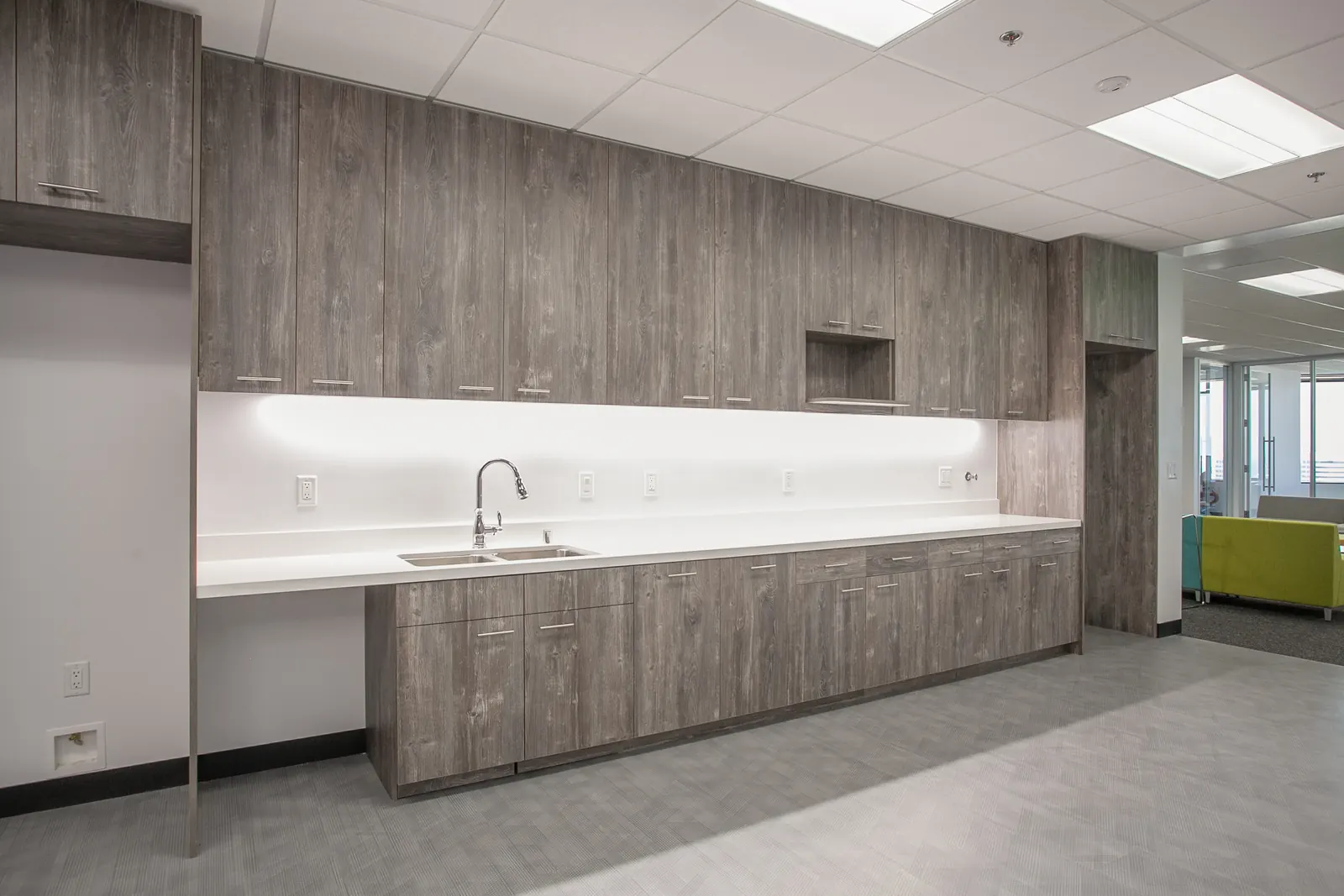 Commercial break room kitchen cabinetry with countertops and appliance integration in Woodland Hills CA